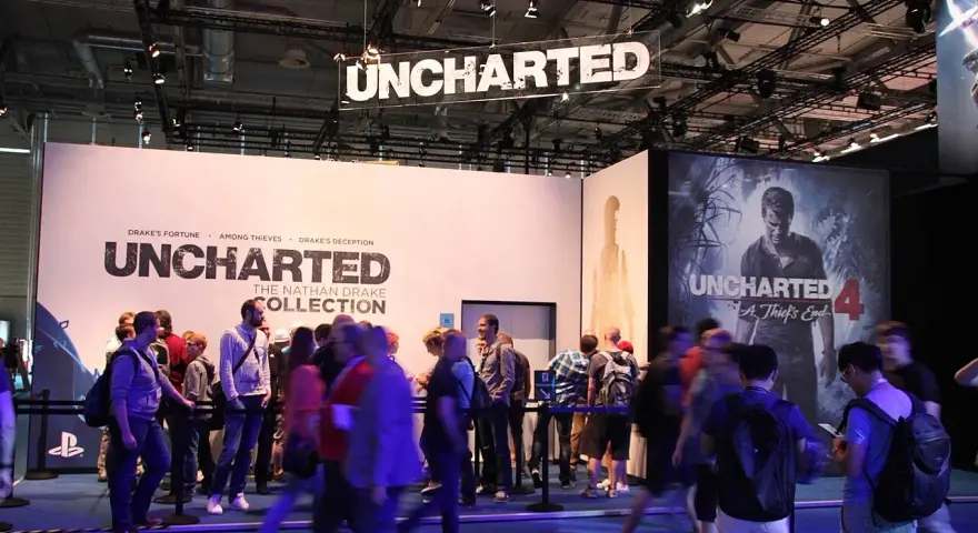 Gente en un evento de videojuegos, con carteles de Uncharted 4 y The Nathan Drake Collection. Se ven varios capítulos de Uncharted.