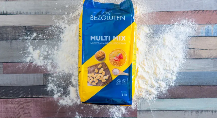Opakowanie mąki Bezgluten Multi Mix, rozsypana mąka na drewnianym tle. To najzdrowsza mąka bezglutenowa do Twoich wypieków.