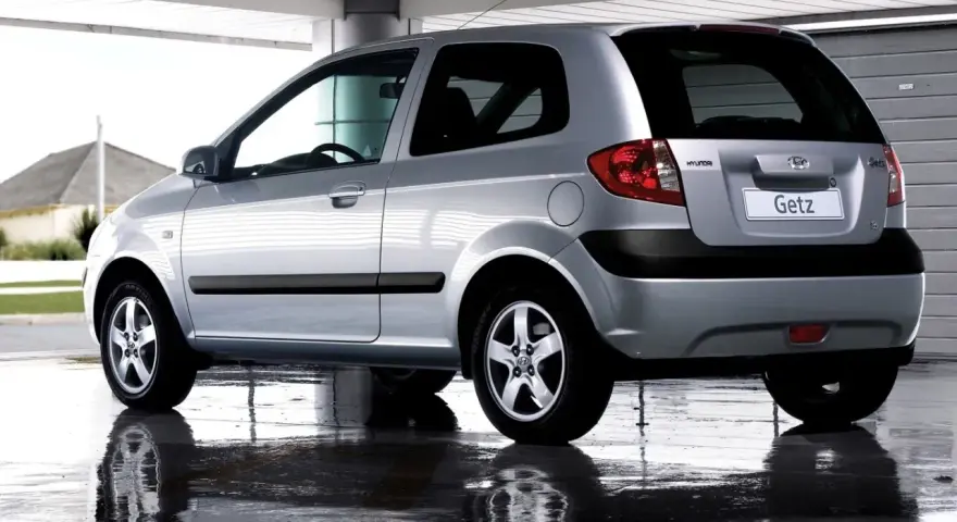 Srebrny Hyundai Getz 1.1 z czarnymi listwami, odbijający się w mokrej nawierzchni pod zadaszeniem.