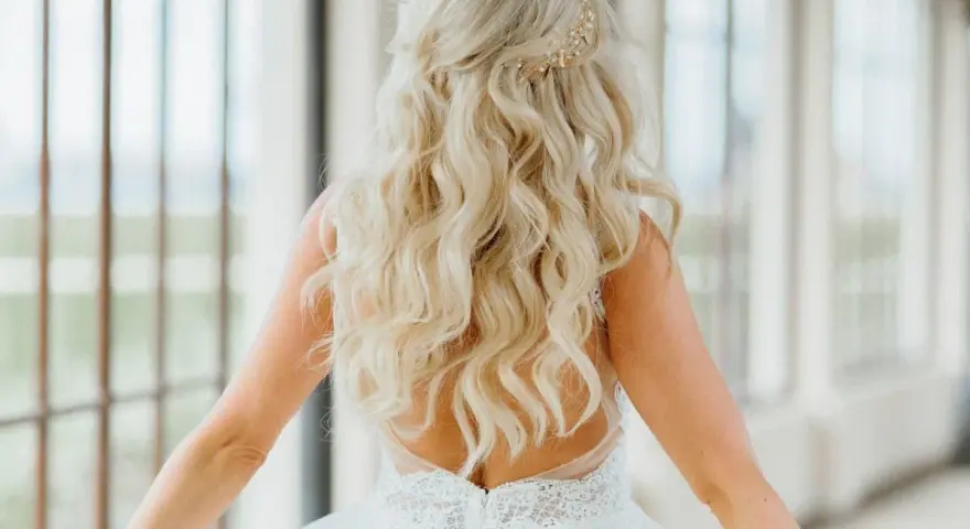 Długie, falowane blond włosy ozdobione złotą spinką. Fryzura w stylu lat 20. idealna na ślub.