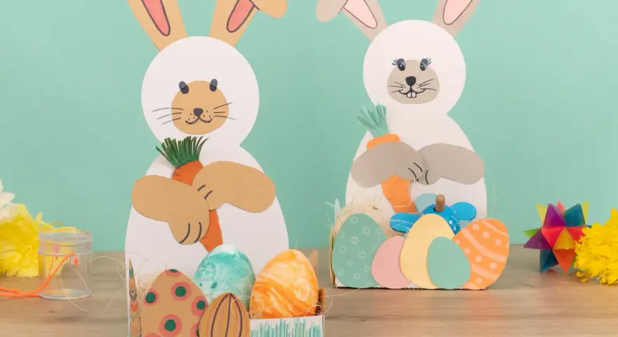 Zwei süße Osterhasen halten Karotten. Kinder haben diese tollen Osterdeko zum Thema Osternest basteln Kinder selbst gemacht.