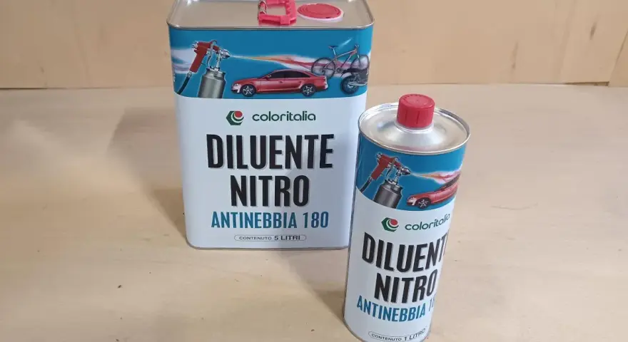Due barattoli di diluente nitro Coloritalia, uno da 5 litri e uno da 1 litro, con grafica di auto e bici. La differenza tra diluente sintetico e nitro è nella composizione.