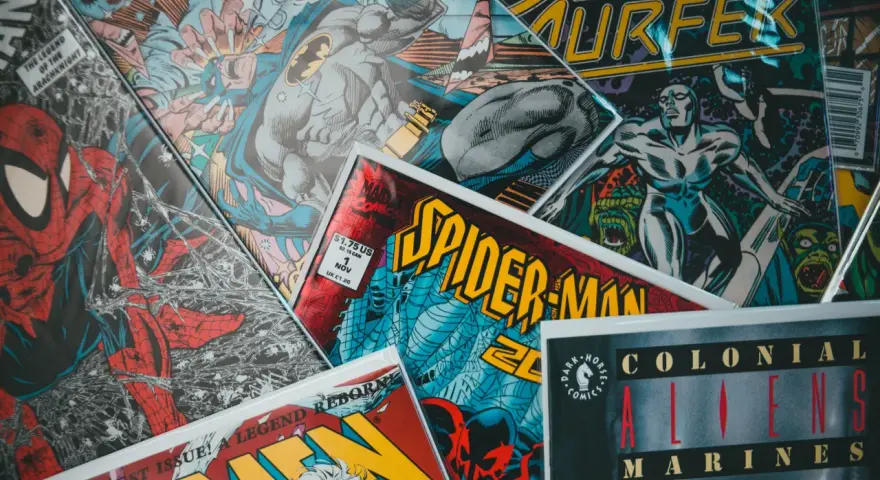 Stos komiksów z postaciami takimi jak Spider-Man, Batman i Silver Surfer. Czy komiks to książka? To zależy od tego, jak na to spojrzeć!