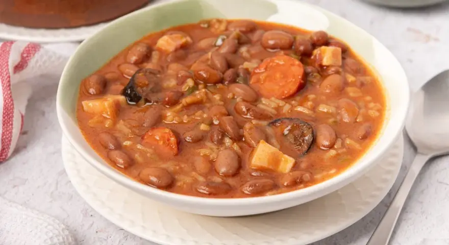 Un tazón de judías pintas con chorizo, patatas y arroz en un guiso meloso.