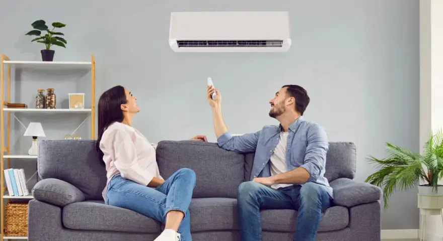 Pareja ajustando el aire acondicionado para encontrar la temperatura ideal y ahorrar energía.
