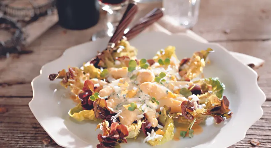 Omas Spargelsalat mit cremigem Dressing, Eiern und Kräutern, serviert auf einem weißen Teller mit Salatblättern.
