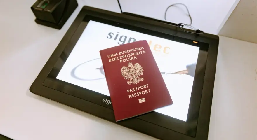 Polski paszport na ekranie tabletu w biurze paszportowym w Poznaniu. Obok skaner linii papilarnych.