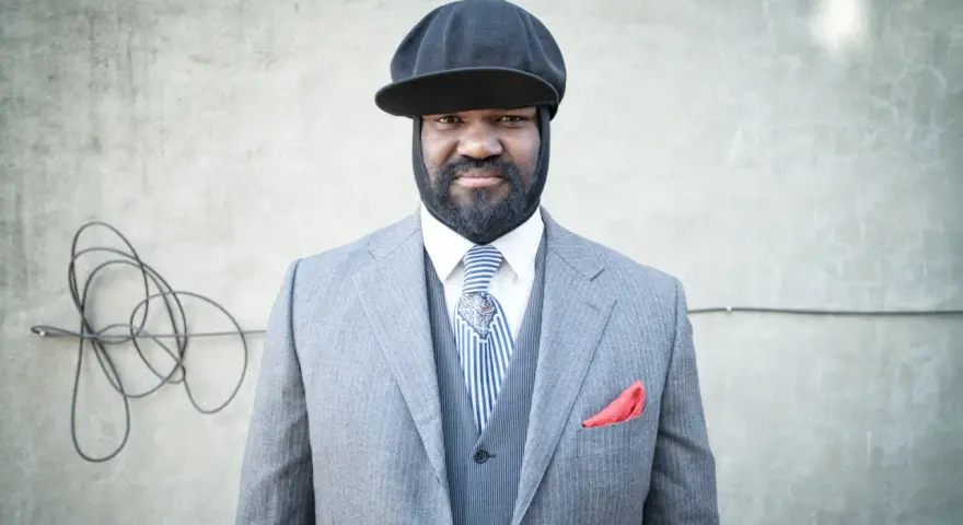 Gregory Porter w eleganckim garniturze i czapce, gotowy na koncert.