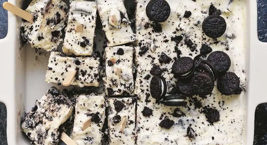 Oreo glass recept: krämig glass med krossade Oreos och hela kakor, skuren i bitar med träpinnar. Perfekt sommardessert!