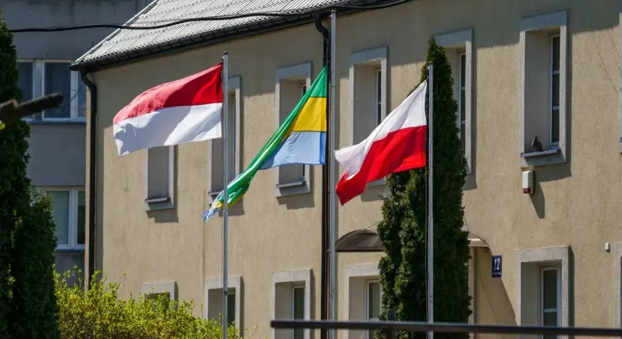 Trzy flagi powiewają przed budynkiem: biało-czerwona flaga Polski, flaga Monako (identyczna jak Indonezji) i flaga Gabonu.