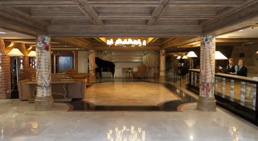 Eleganckie lobby hotelowe z fortepianem, recepcją i dwoma pracownikami.