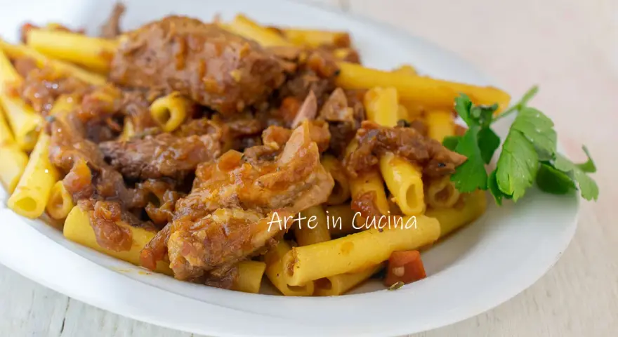 Piatto di ziti alla genovese con ragù di carne e cipolle caramellate, guarnito con prezzemolo fresco.