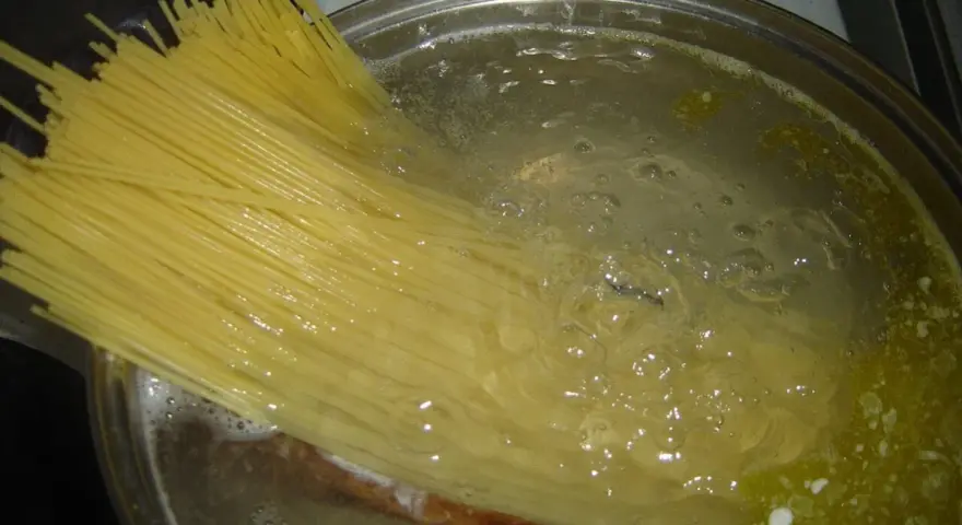 Długi makaron spaghetti gotuje się w bulgoczącej wodzie. Czas, **ile gotować makaron**, zależy od jego grubości.