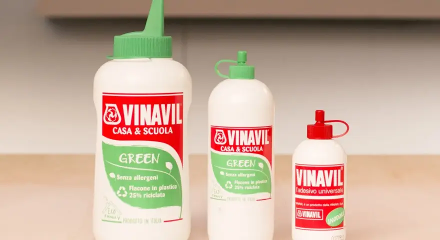 Tre flaconi di colla Vinavil, un adesivo universale pva glue cos'è, in diverse misure, con tappi verdi e rossi.