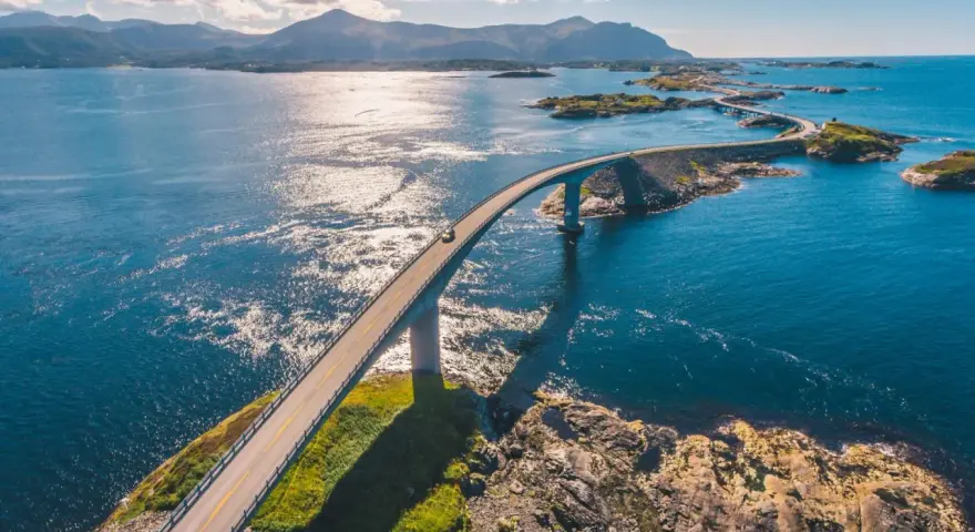En bil kör över en bro i Norge, en del av den fantastiska Atlantvägen. En dröm att åka till Norge och uppleva detta!