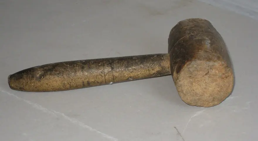 Un vecchio mazzuolo di legno, strumento che evoca il suo significato di forza e lavoro manuale.