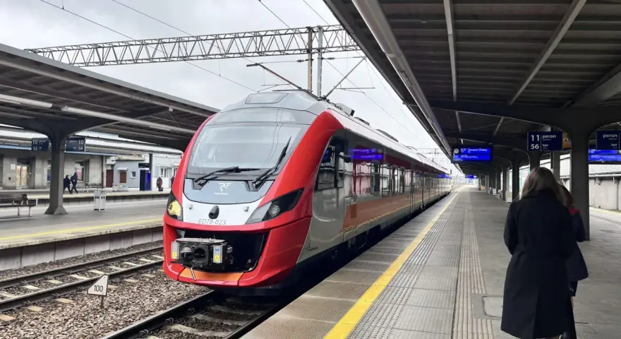 Czerwono-szary pociąg POLREGIO na peronie dworca kolejowego.