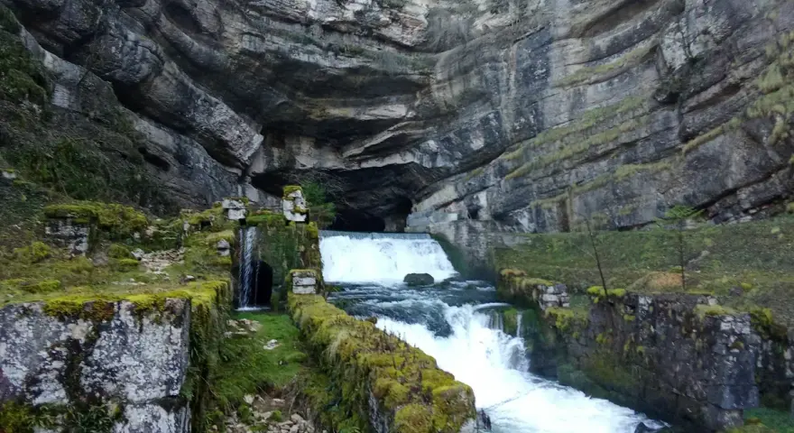 La source de la Loue, un spectacle naturel impressionnant. L'itinéraire mène à travers ce paysage rocheux où l'eau jaillit d'une grotte.