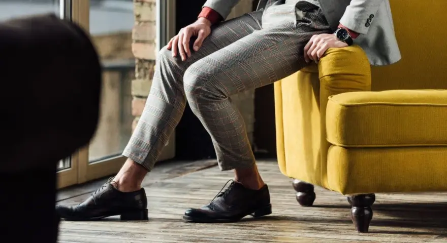 Eleganckie, ciemnobrązowe buty męskie do szarego garnituru w kratę. Stylizacja idealna na co dzień i specjalne okazje.