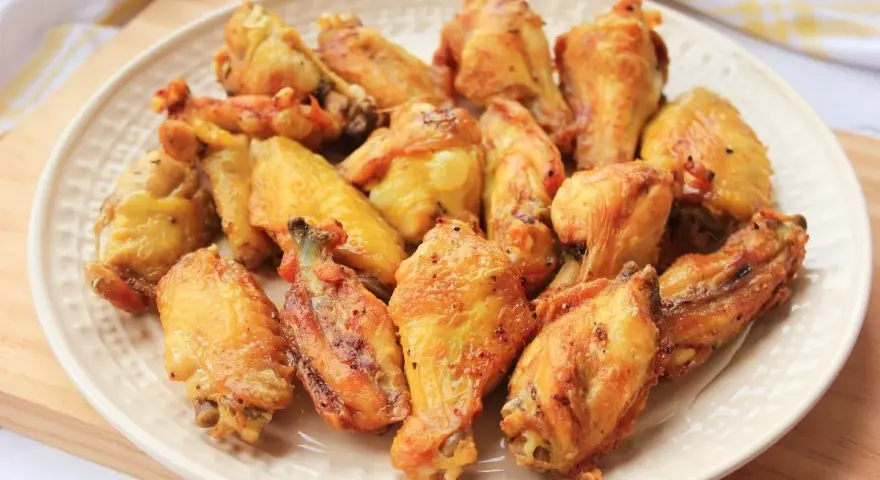 Alitas de pollo doradas y crujientes en un plato blanco.
