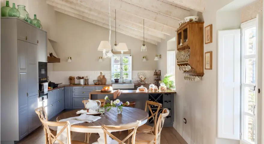 Cocina rústica y acogedora. Ideas para decorar casa vieja de pueblo con poco dinero. Techos de madera, muebles grises y mesa redonda.