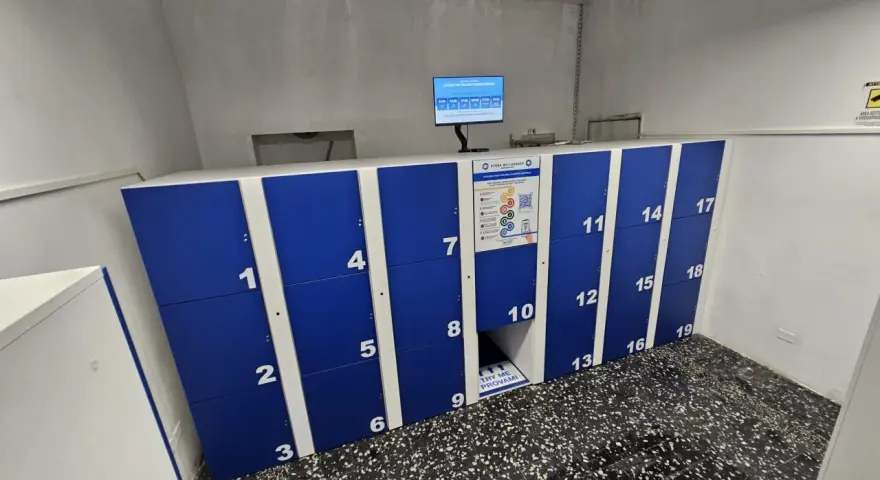 Blue and white numbered luggage lockers with a digital screen and instructions.