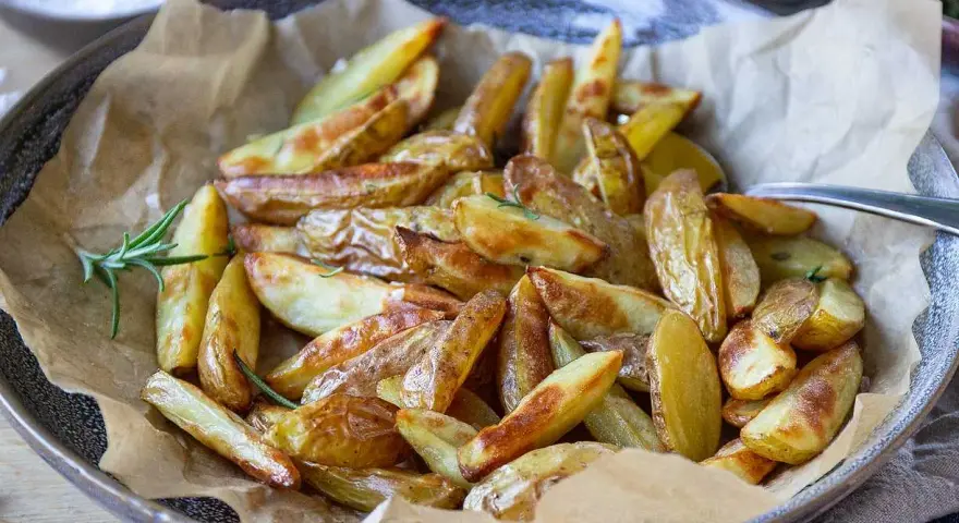 Klyftpotatis i airfryer, gyllene och krispiga, serverade med rosmarin. Perfekt tillbehör!