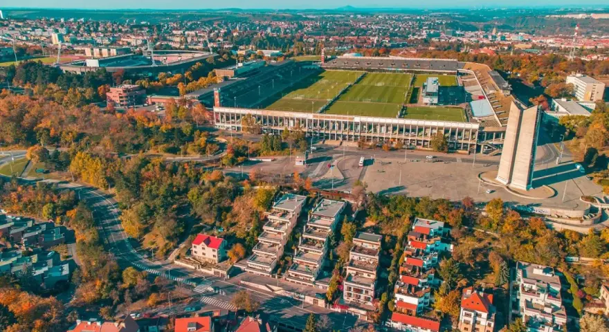 Widok z lotu ptaka na imponujący stadion, największy stadion w Europie, otoczony jesienną zielenią i nowoczesną zabudową.