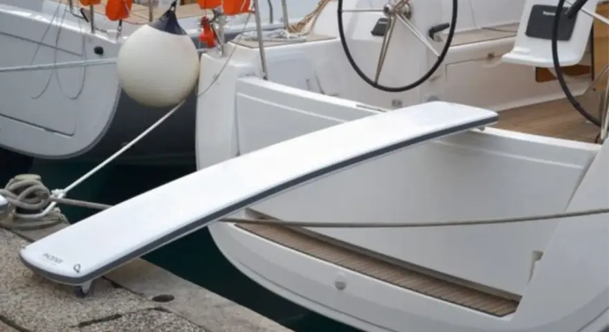 Eine selbstgebaute Gangway für Boote, die über eine Reling gelegt wird.