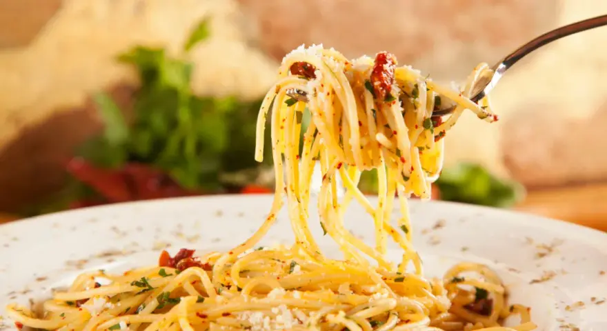 Widok z bliska na widelec z porcją spaghetti, posypane parmezanem i ziołami. Idealne jakie przyprawy do spaghetti!