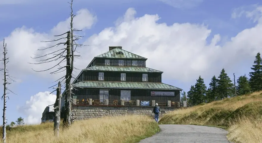 Schronisko Odrodzenie w Karkonoszach, z charakterystyczną architekturą i otoczone suchymi drzewami.