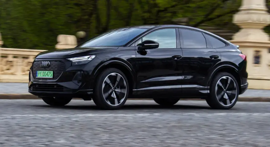 Czarny Audi Q4 e-tron w ruchu. Sprawdź, jaki jest jego zasięg na jednym ładowaniu.