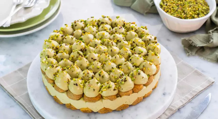 Torta rotonda con tante piccole meringhe verdi e granella di pistacchio, un delizioso tiramisù al pistacchio.