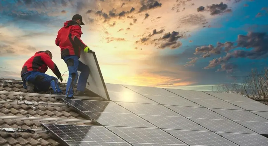 Instalatorzy montują panele fotowoltaiczne, by zapewnić maksymalną wydajność i czystą energię. Zachód słońca dodaje uroku.