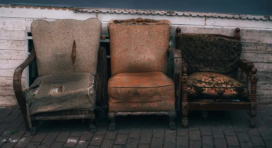 Trzy zniszczone fotele, które wyglądają, jakby czekały na to, gdzie wywieźć stare meble.