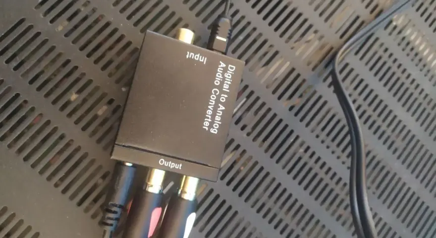 Konwerter cyfrowo-analogowy audio z podłączonymi kablami RCA i optycznym.