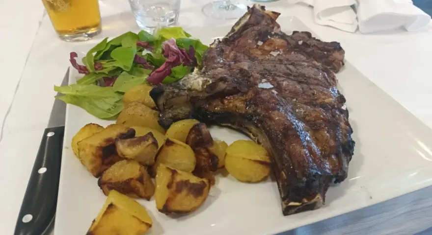 Succulenta costata di manzo alla griglia, servita con patate arrosto croccanti e un'insalata fresca. Un piatto da vero intenditore.