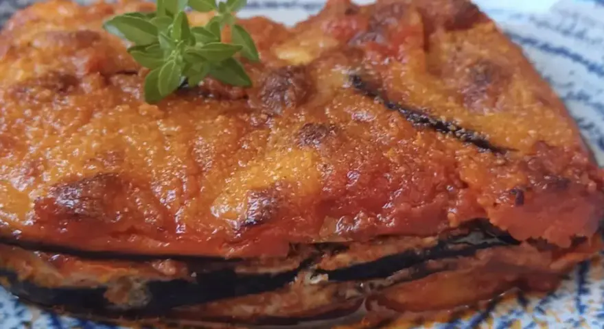 Parmigiana in padella, uno strato di melanzane fritte, pomodoro e formaggio, guarnita con basilico fresco.