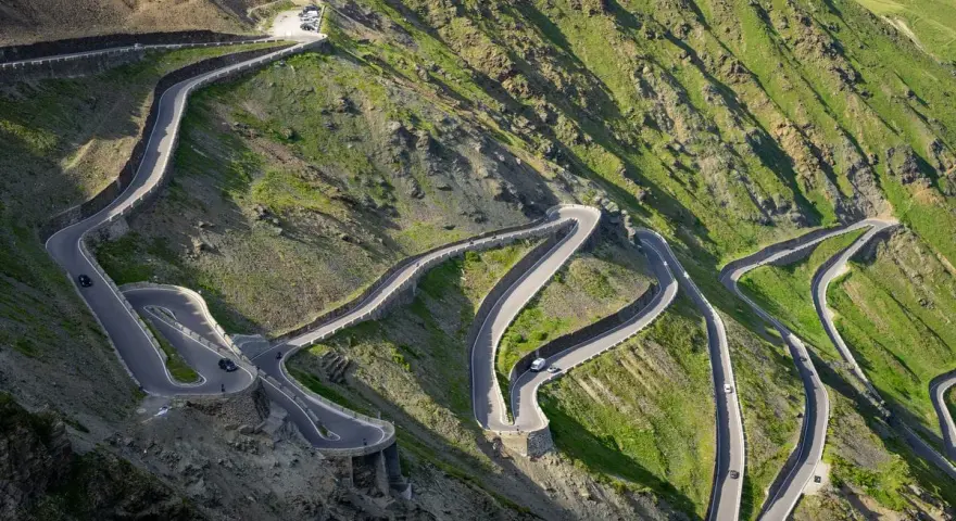Strada tortuosa che sale verso il passo più alto d'Europa, con tornanti stretti e panorami mozzafiato.