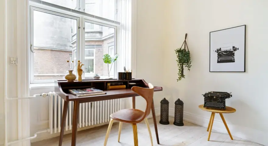 Ett elegant skrivbord i oljad ek med en läderklädd stol. En gammal skrivmaskin står på ett litet sidobord.