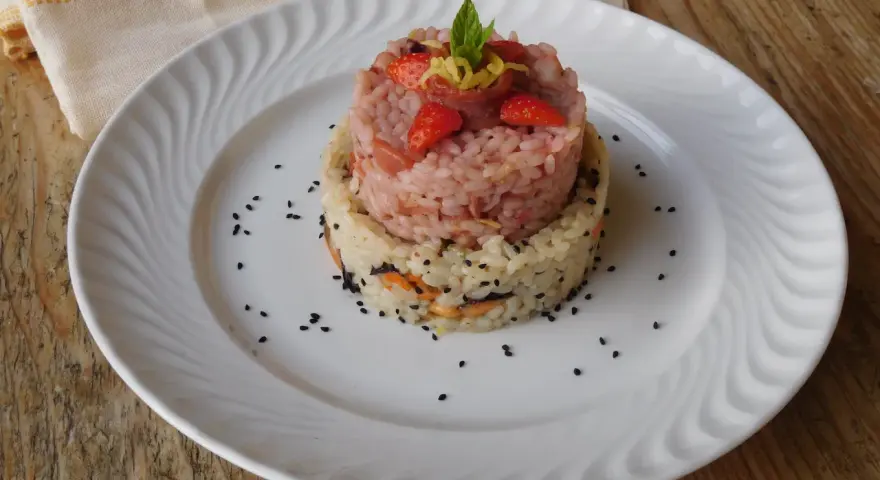 Due torri di riso, una rosa con fragole e menta, l'altra bianca con verdure e semi neri. Un piatto che ricorda la crema di riso.