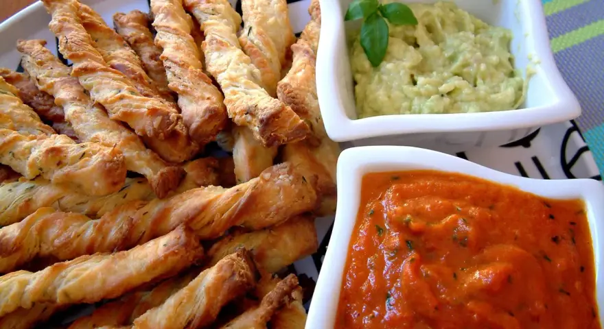 Chrupiące paluszki grissini z ziołami, idealne do podania z kremowym guacamole i pikantnym sosem pomidorowym.