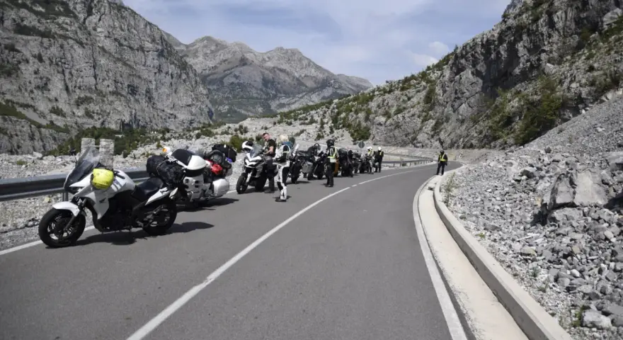Grupa motocyklistów zatrzymała się na malowniczej drodze w Albanii, podziwiając spektakularne widoki gór.