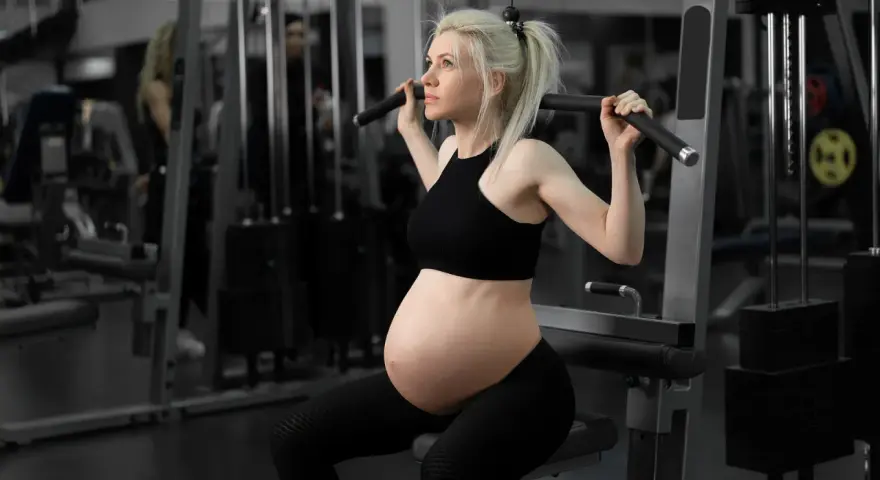 Gravid kvinna tränar marklyft i gym.
