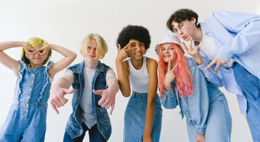 Ragazzi con un look anni '90, tutti vestiti di jeans, fanno pose divertenti.
