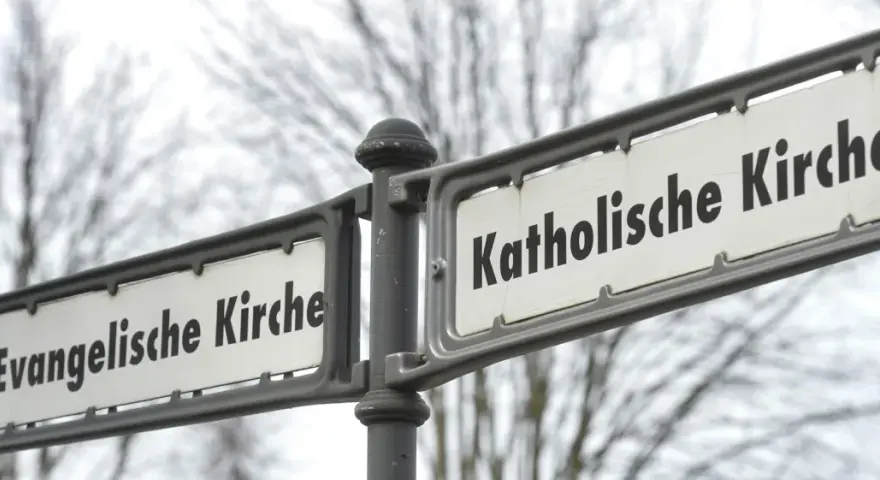 Straßenschilder weisen den Weg zur Evangelischen und Katholischen Kirche. Ein sichtbarer Unterschied katholisch evangelisch.