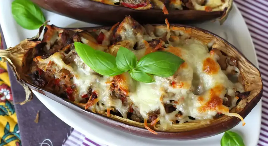 Melanzane ripiene al forno velocissime, dorate e filanti, guarnite con basilico fresco. Un piatto invitante e facile da preparare.
