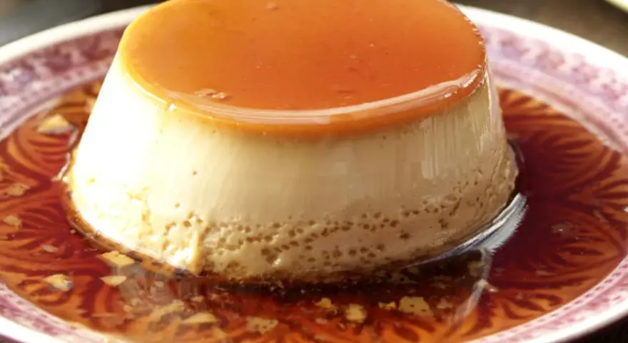 Delicioso flan de café con caramelo líquido, servido en un plato con un diseño intrincado.