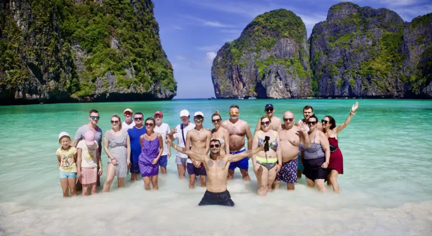 Grupa ludzi cieszy się słońcem i turkusową wodą na plaży Maya Bay.