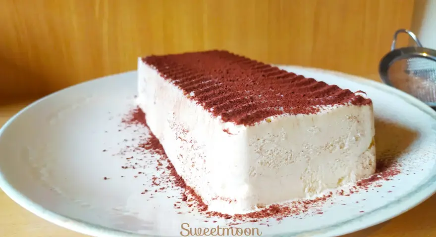 Un delizioso semifreddo al caffè, cosparso di cacao amaro, attende su un piatto bianco.